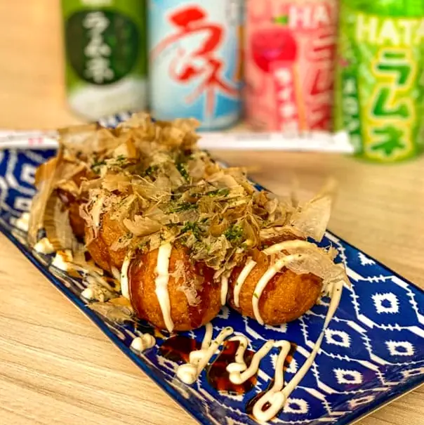 Takoyaki z płatkami bonito i majonezem, w tle butelki ramune